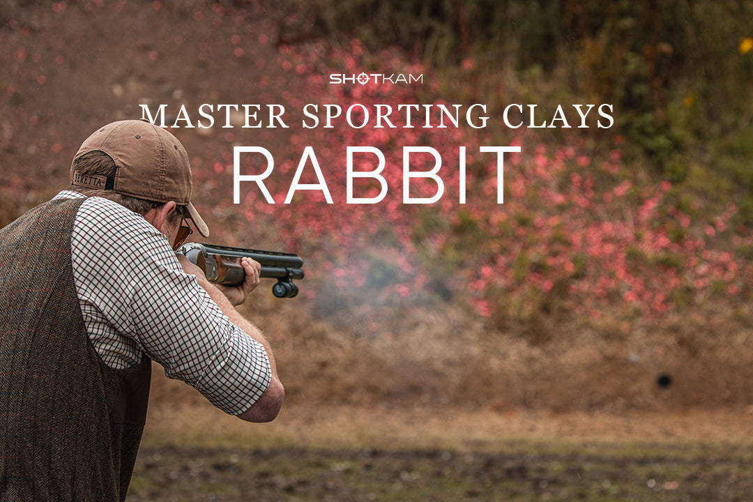 Sporting clays shooter taking a controlled swing-through shot at a rabbit presentation.