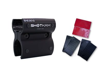 ShotKam 20 Gauge Side-by-Side mount bracket in black aluminum, displayed alongside extra rubber pads and red adhesive strips. The mount features internal rubber lining for a secure, scratch-free attachment to shotgun barrels. Compatible with ShotKam Gen 3 and Gen cameras.